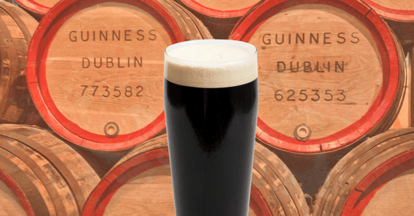 A pint of Guinness against a background of Guinness barrels.