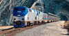 An Amtrak train on the tracks against a blue splattered background.