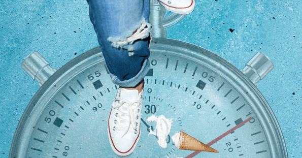 A person’s legs in jeans and sneakers, with an ice cream cone on the floor and a stopwatch in the background.