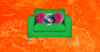 A green arm chair with two round, pink throw pillows and a photo of earth on it.