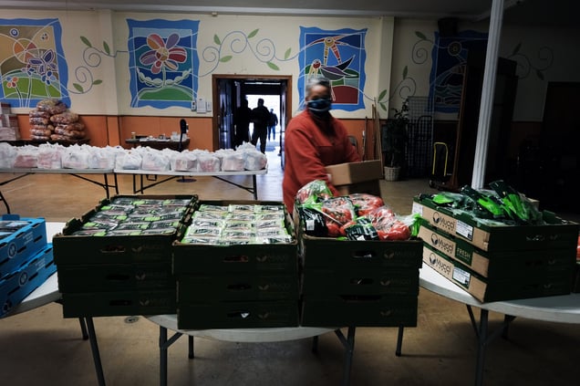 Volunteers stocking a food pantry with boxes of fresh produce and packaged goods in Kensington.