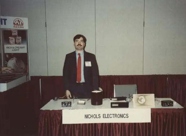 Mark Nichols standing at a vendor table in a convention center