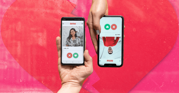 Two white hands holding smartphones with a man’s dating app profile on one and a woman’s on another on a pink background with the outline of a broken heart.