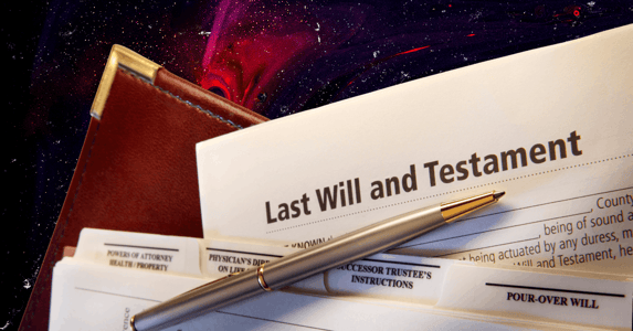 A document labeled 'Last Will and Testament' in front of a leather folder. A silver pen rests on top.