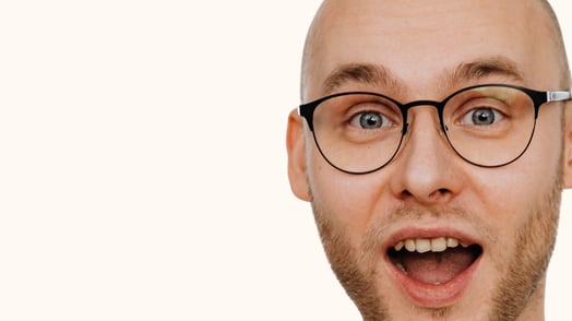 A man wearing glasses has an excited expression on his face.