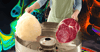 A person in a green apron spins cotton candy out of meat.