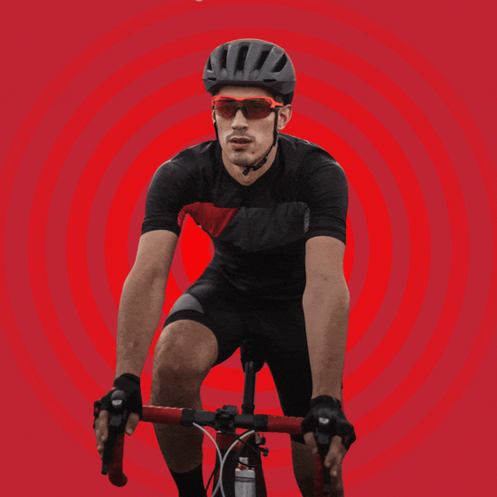 A man in cycling clothes, gloves, and a helmet riding a bike.