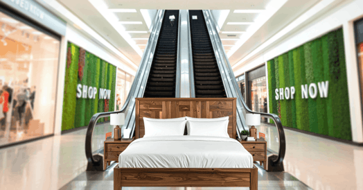 A bed sits at the foot of an escalator in a shopping mall. 