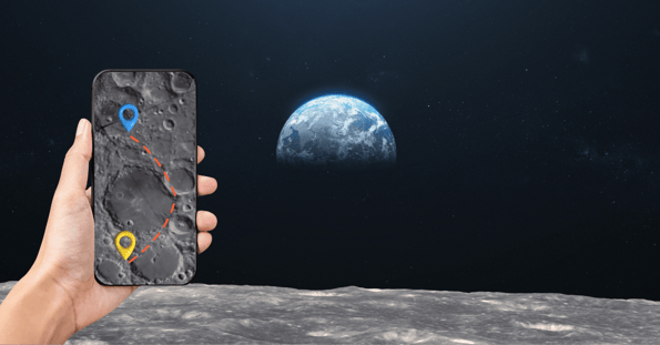 A hand holding a cellphone with a map of the moon appears to belong to someone standing on the surface of the moon.