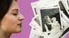 A woman sniffs a collection of black and white photographs. 