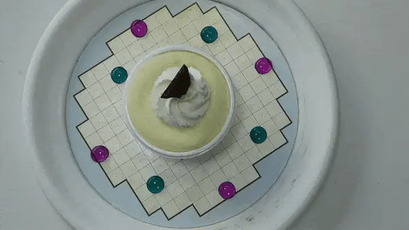 A GIF shows a dinner plate from overhead as green and purple liquid droplets shift around independently.