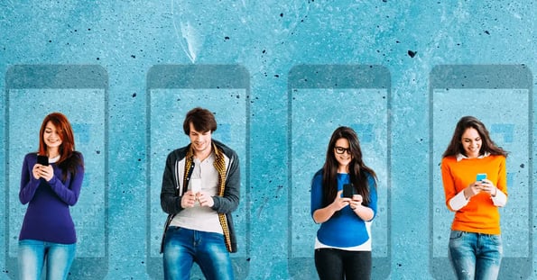 Four young people all standing and smiling at their smartphones while texting in front of the faded outlines of iPhones in the background.