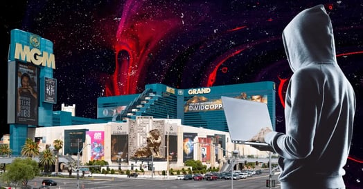 A man in a gray hoodie holding a laptop outside of an MGM casino on a red-and-black and swirled background.