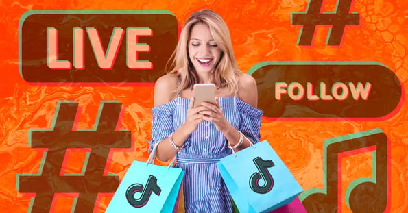 A blonde woman in a blue dress holding two shopping bags with the TikTok logo on the front smiling at her cellphone.