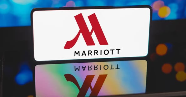 Marriott hotel logo on a smartphone with the reflection showing on a table beneath the phone.