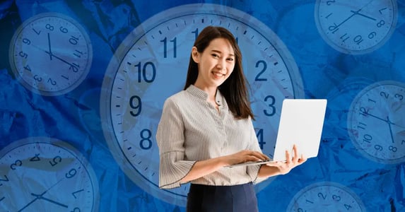 A woman holding a laptop with clocks in the background.