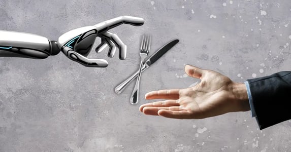 A robot hand and a white male hand in a suit jacket both reaching for a silver fork and knife on a gray background.