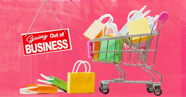 A shopping cart filled with colorful bags and a red “Going out of business” sign.