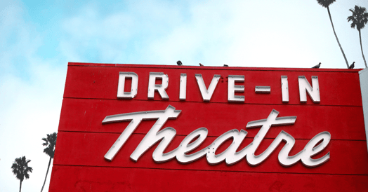A sign that reads 'drive-in theater' flanked by palm trees. 