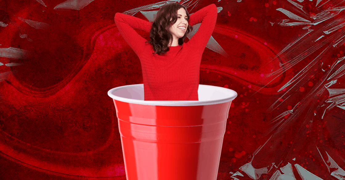 A white, brunette woman in a red sweater emerges from a red Solo cup.