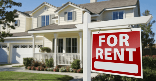 A pale yellow house with a For Rent sign in front. 