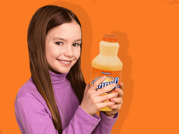 A girl holding a bottle of orange juice, showcasing her enjoyment of the refreshing beverage.