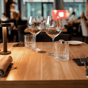 A hand slides a white dinner plate with a stack of cash on it across a table in a restaurant.