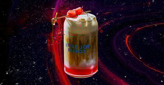 A raspberry danish latte from Little Joy Coffee in a branded glass. (Little Joy Coffee)