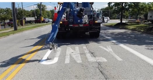 A robot arm attached to a truck repaints the word 