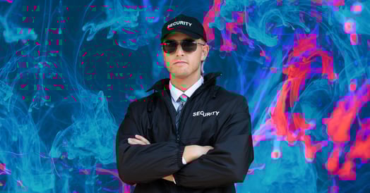 A security guard in a black jacket, hat, and sunglasses.
