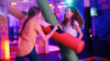 Two young girls laugh as they play with large foam 'battle beams'