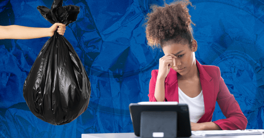A woman in a pink blazer sits at her desk with her head in her hands while an arm extends her a black garbage bag.