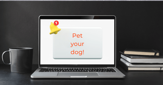 A laptop screen displays a large “Pet your dog!” notification.